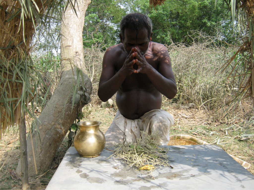 বাহারবে শালফুলকে ভক্তি করছেন এক সাঁওতাল